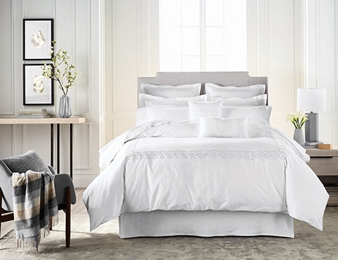 The palest gray walls flatter a bedroom with fluffy white bedding.