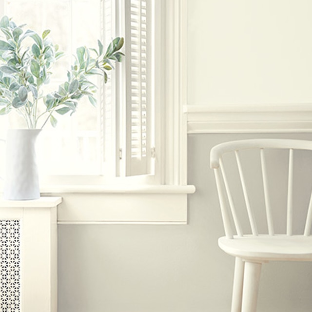 Varying shades of white paint colours on walls, trim, and wainscoting, and a white chair by window.