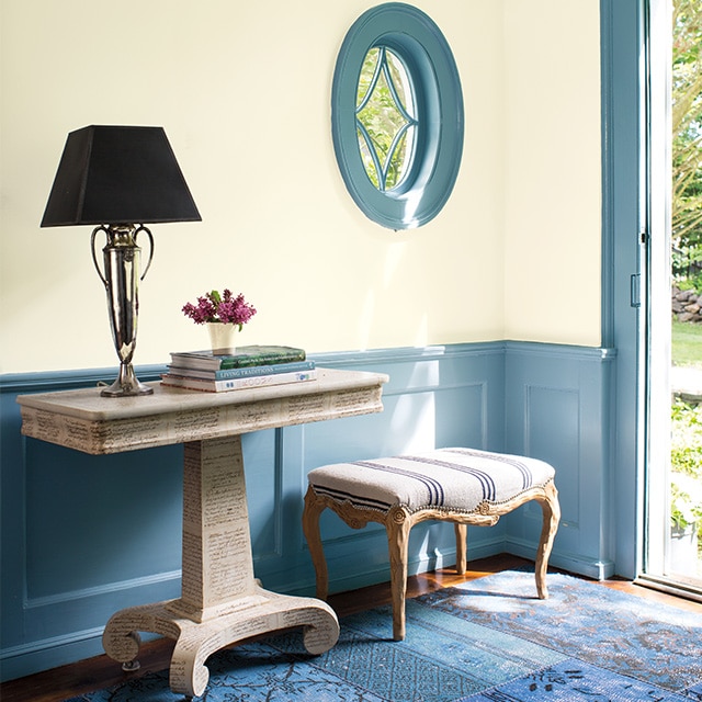 A welcoming entryway with off-white painted walls and pretty blue wainscoting, window and door trim.