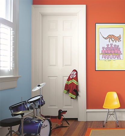 Orange and blue walled play area with dinosaur painting, small yellow chair, blue drum set, and child's fireman jacket.