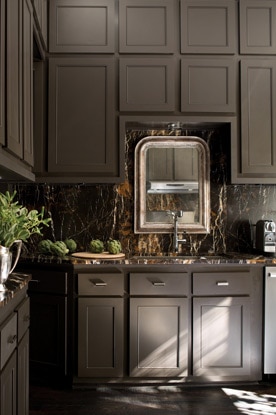 Rich brown kitchen cabinets, brown marble backsplash and an ornate mirror create a sumptuous culinary setting.