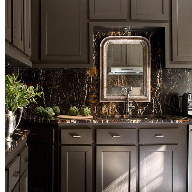 Rich, brown-painted kitchen cabinets, a brown marble backsplash and an ornate mirror create a sumptuous culinary setting.