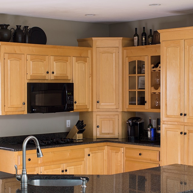 Una cocina con gabinetes de madera, encimeras negras y electrodomésticos antes de una renovación completa.