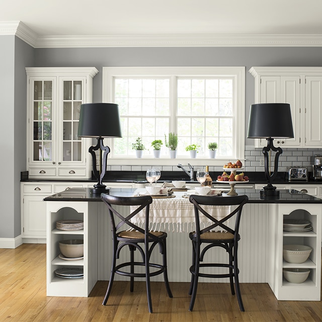 This light gray-painted kitchen keeps it fresh with white cabinetry and subway tile backsplash, adding a dash of depth with black countertops.