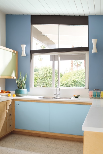 Une cuisine peinte dans des tons de bleu, dont les armoires et les comptoirs arborent des accents de beige et de blanc.