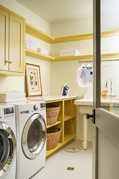A cream laundry room with built-in shelves and cabinets in a mid-tone yellow color.  