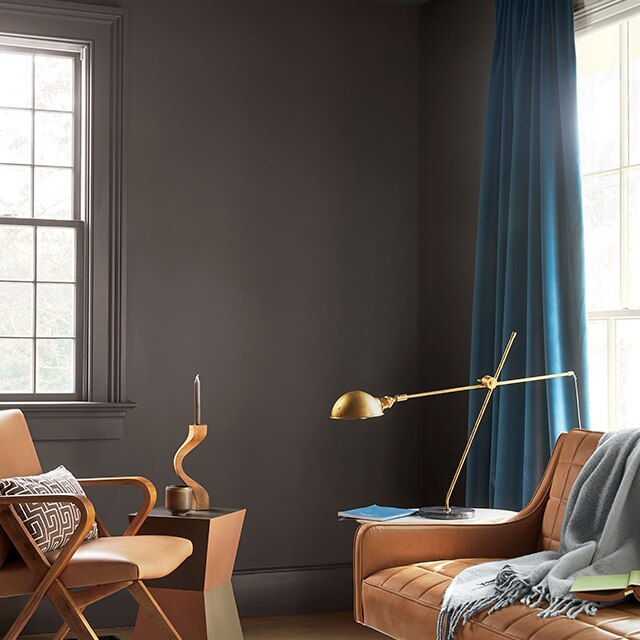 A rich charcoal-brown painted living room space with contemporary furnishings and Teal drapes.