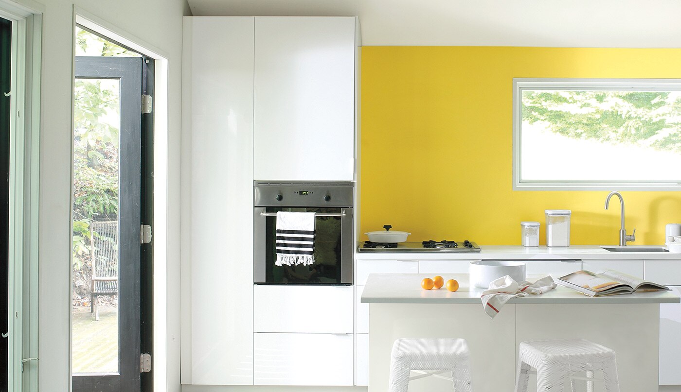 A modern kitchen with a navy blue and white striped floor runner and a bright yellow-painted accent wall.
