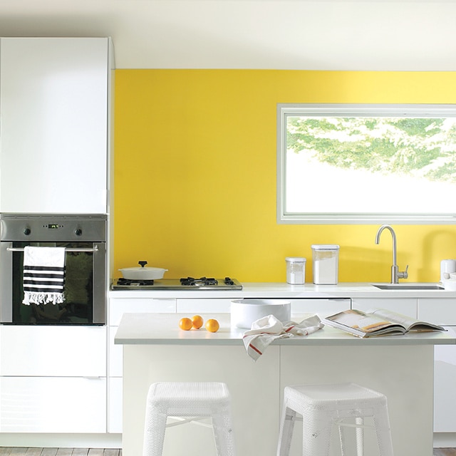 A modern kitchen with a navy blue and white striped floor runner and a bright yellow-painted accent wall.