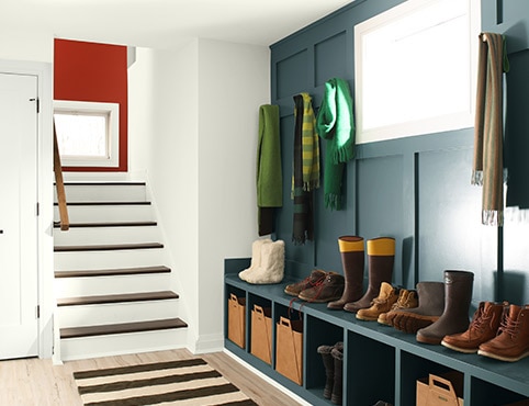 A white hallway with a deep blue accent wall that includes a built in bench and cubbies.