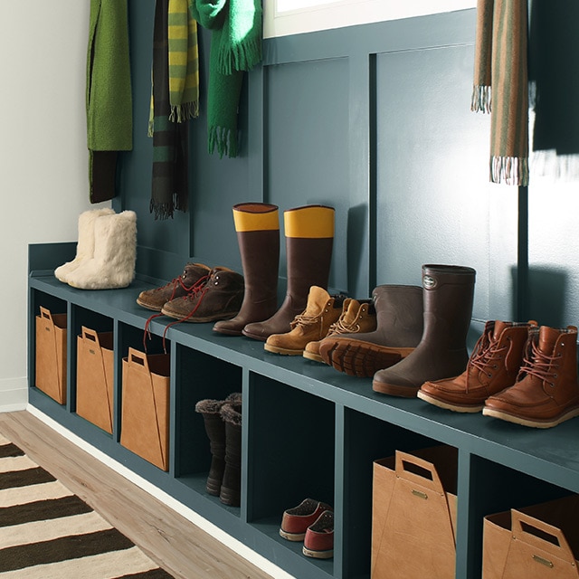 A white hallway with a deep blue accent wall that includes a built in bench and cubbies.