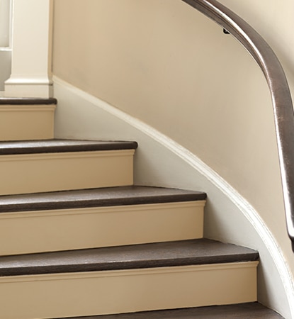 Escalier tournant de couleur café avec rampe et marches brun chocolat.