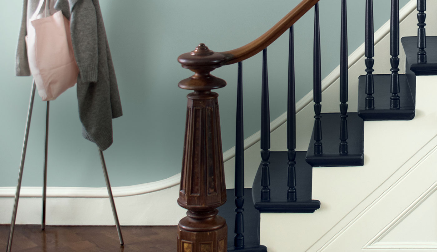 Entryway staircase with wood handrail, newel and navy-painted staircase.