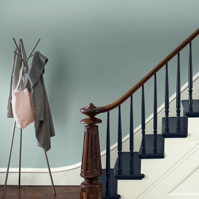 Entryway staircase with wood handrail, newel and navy-painted staircase.