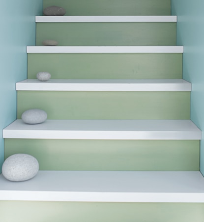 Seafoam green and white stairs nestled between light blue walls. Seafoam green and white stairs nestled between light blue walls.
