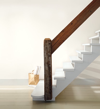 Bright and airy room with white staircase and natural wood railing.