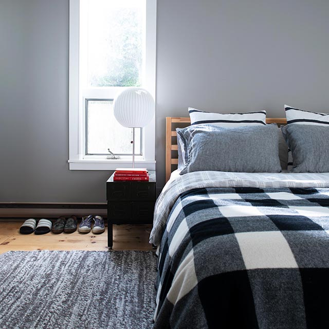 A gray-painted bedroom with white shiplap ceiling and bed with plaid bedding.