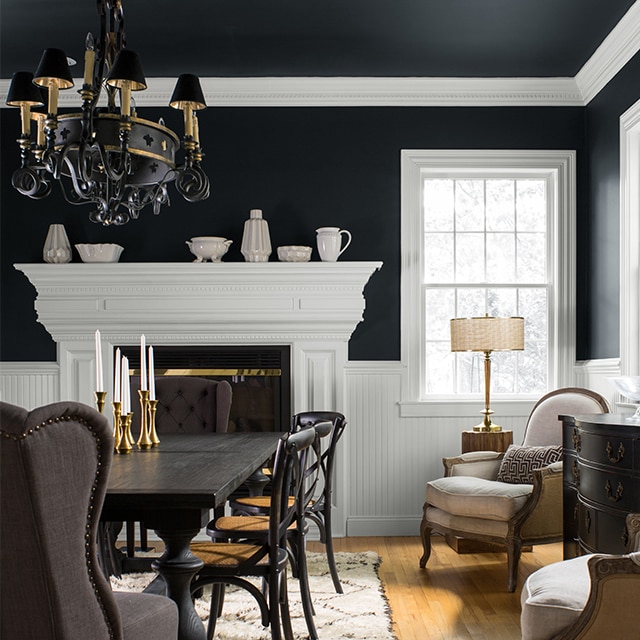 Grande salle à manger avec des murs et un plafond noirs spectaculaires et des moulures blanches.