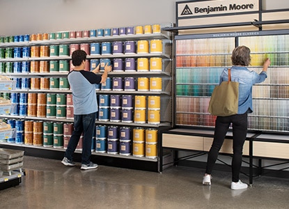 Customers peruse cans of paint and colour chip samples in a Benjamin Moore retailer store.  