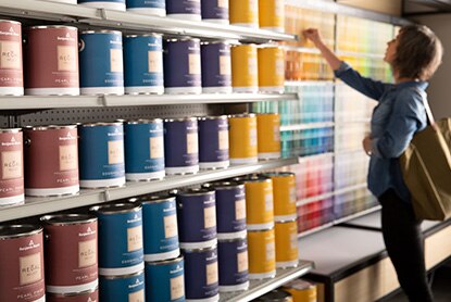 A homeowner looking at paint display chips in a Benjamin Moore retail store.