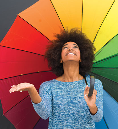 A woman stands under a multicoloured umbrella