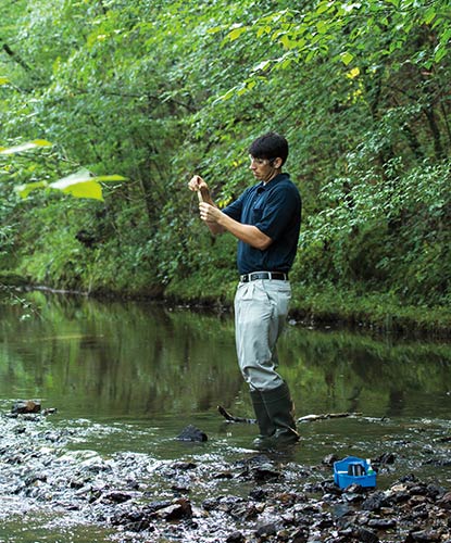 A Benjamin Moore employee tests water from a creek on our premises.