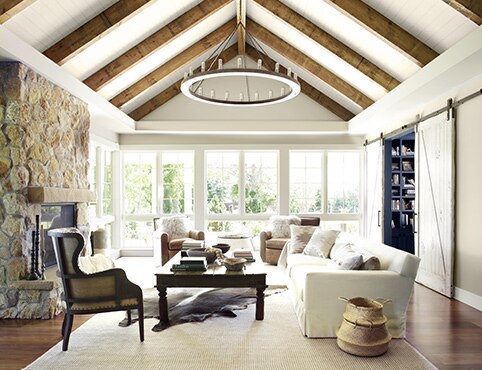 Greige-painted living room with white vaulted shiplap ceiling featuring exposed wood beams.