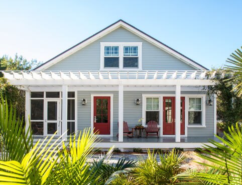 Maison lumineuse du Sud-est peinte en gris-bleu pâle avec portes d’entrée en rouge Caliente AF-290.