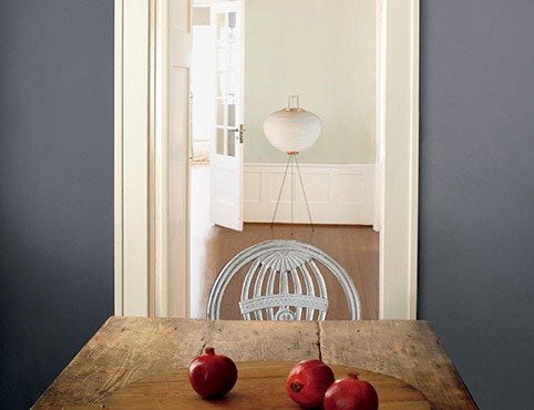 Mesa rústica de tablones con pared azul grisácea y granadas.