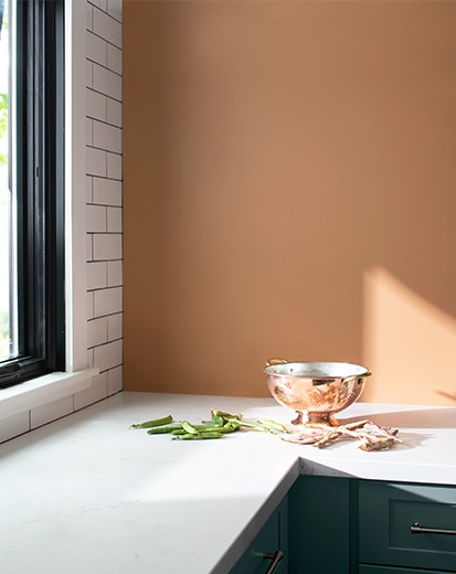 Kitchen with peach-painted walls, subway tile accent wall, blue counters with white tops, and a brass bowl.