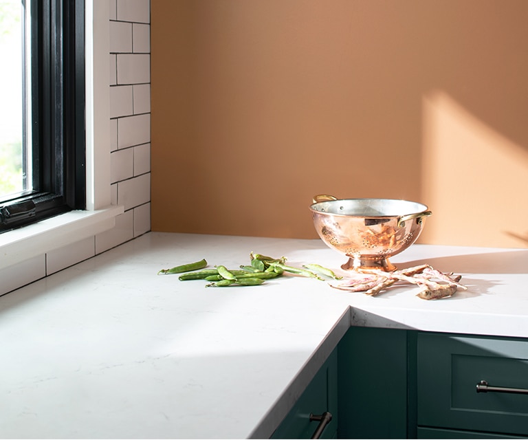 Kitchen with peach-painted walls, subway tile accent wall, blue counters with white tops, and a brass bowl.