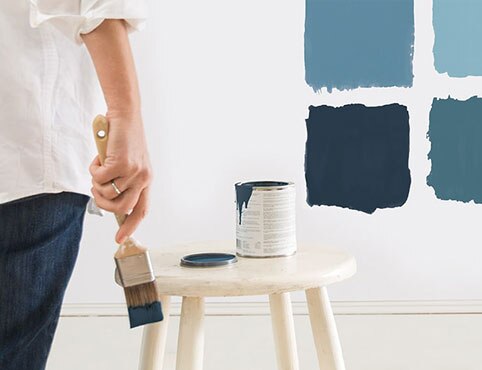 A homeowner sampling different interior blue paint colors.