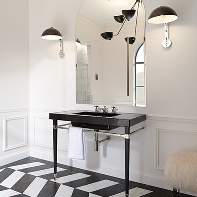 A bathroom with off-white-painted walls, a black sink, black lights, and black and white marble chevron floor.