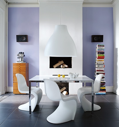 Murs bleu-magenta pâle, cheminée blanche, table de salle à manger et chaises modernes blanches.