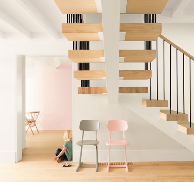 Floating wood staircase in open foyer with white walls and a pink accent wall.