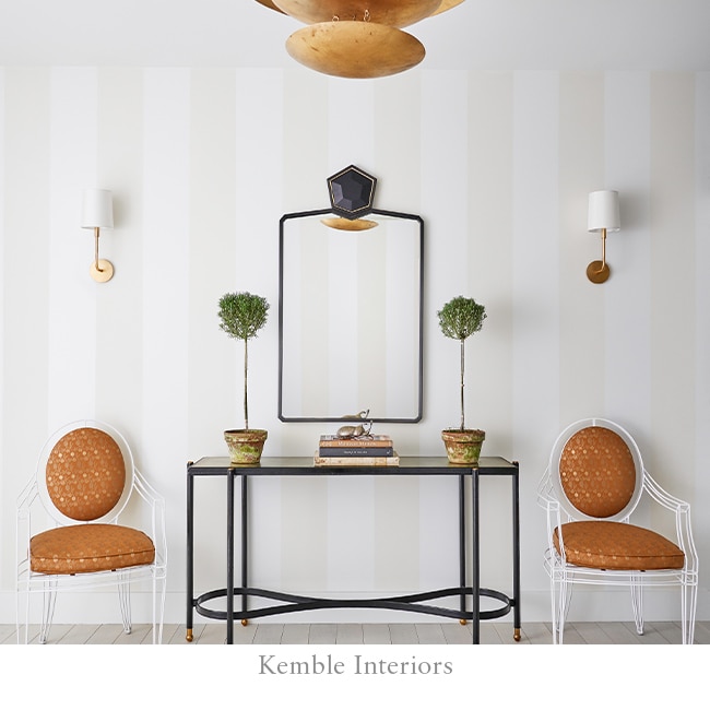 Thick white and gray stripes on entryway wall with two orange chairs aside a table and mirror.