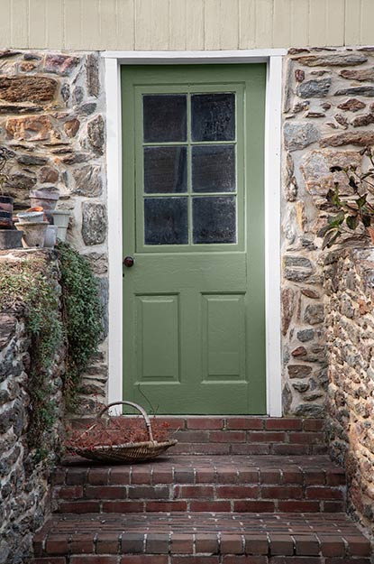 Brick stairs leading up to a green front door surrounded by stacked stone. Brick stairs leading up to a green front door surrounded by stacked stone.