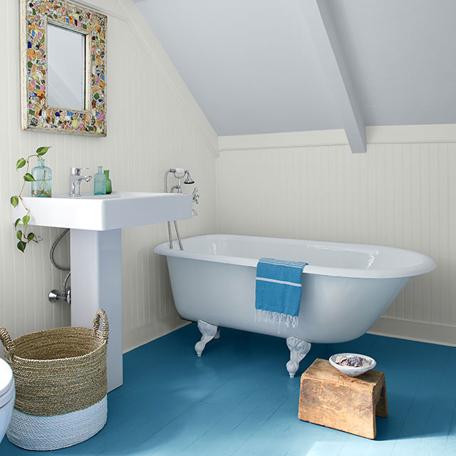 Une salle de bains arborant un plafond et des murs peints en blanc, des appareils sanitaires en porcelaine, des accents rustiques et un plancher peint en bleu aux tons moyens.