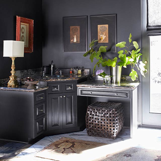 A dark gray entryway with mirror, door with large window, and an accent table with flowers on it.