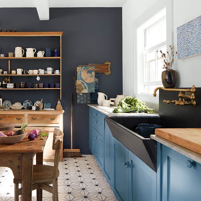 Une cuisine de style patrimoine anglais avec des armoires peintes en bleu, un mur d’accent peint en marine et des meubles en bois.