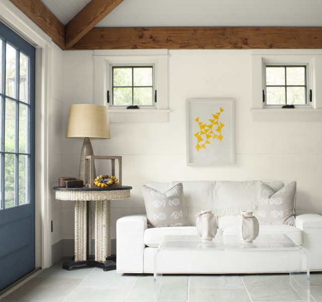 Gray-painted doors provide a warm welcome into this white-painted seating area with white couch and modern furniture.
