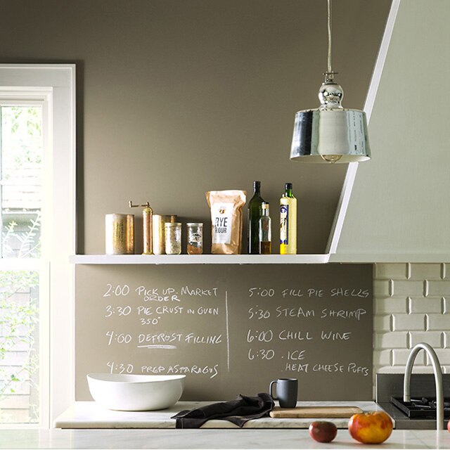 A kitchen with taupe chalkboard walls features a daily schedule; a variety of fruits and kitchen utensils sit on the counter. A kitchen with taupe chalkboard walls features a daily schedule; a variety of fruits and kitchen utensils sit on the counter.