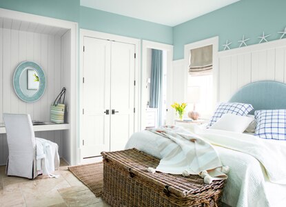 Une chambre à coucher bleu pâle avec des moulures blanches et un meuble-lavabo encastré dans un coin.