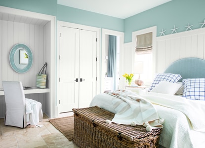 A light-blue painted bedroom with white trim and built-in vanity area.