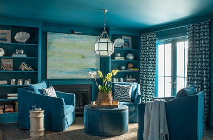 An all-blue living room with blue club chairs and shelving.