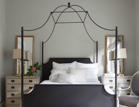 A light gray bedroom features a wrought iron four poster bed. A light gray bedroom features a wrought iron four poster bed.