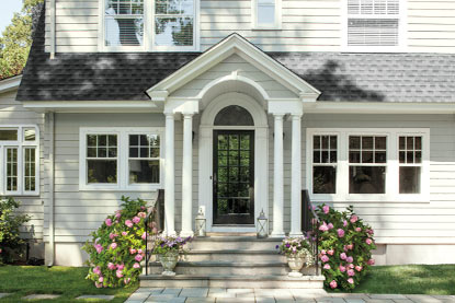 A sun-dappled home exterior features light gray paint.