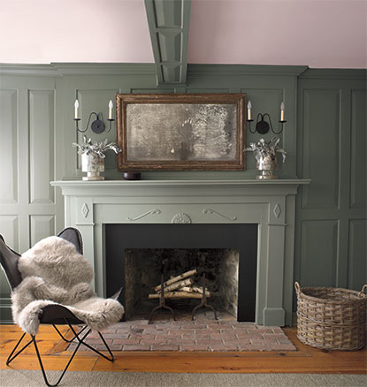 A green-painted living room with matching green mantel and fur throw.