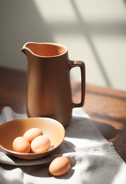A water jug and bowl of eggs set against a wall painted in Wish AF-680.