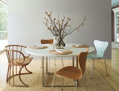 Airy kitchen with gray accent wall and mint ceiling; large paper lantern lighting above circular table with wooden chairs.